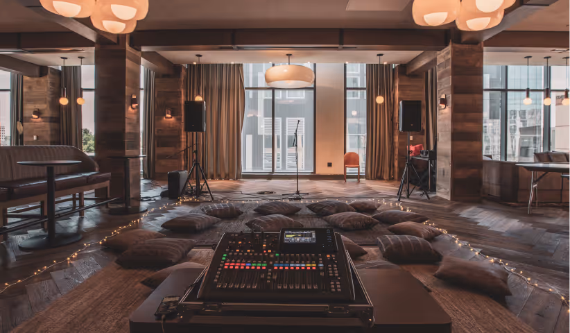 Cozy lounge with a microphone on stage, surrounded by cushions and audio equipment for a live event.