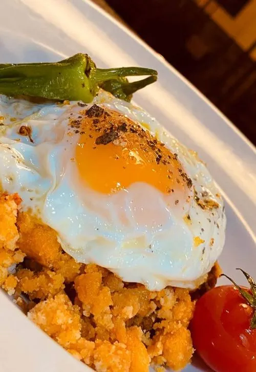 Un plato de migas castellanas con huevo y pimientos de la huerta.