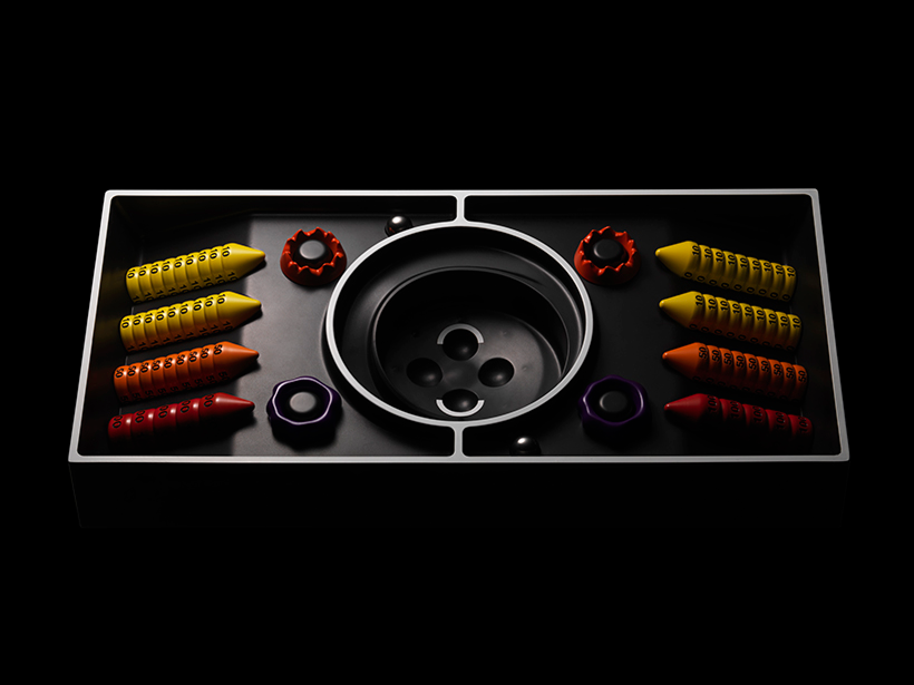 Abstract symmetrical art piece with colorful numbered cones and circular shapes arranged on a black rectangular base.