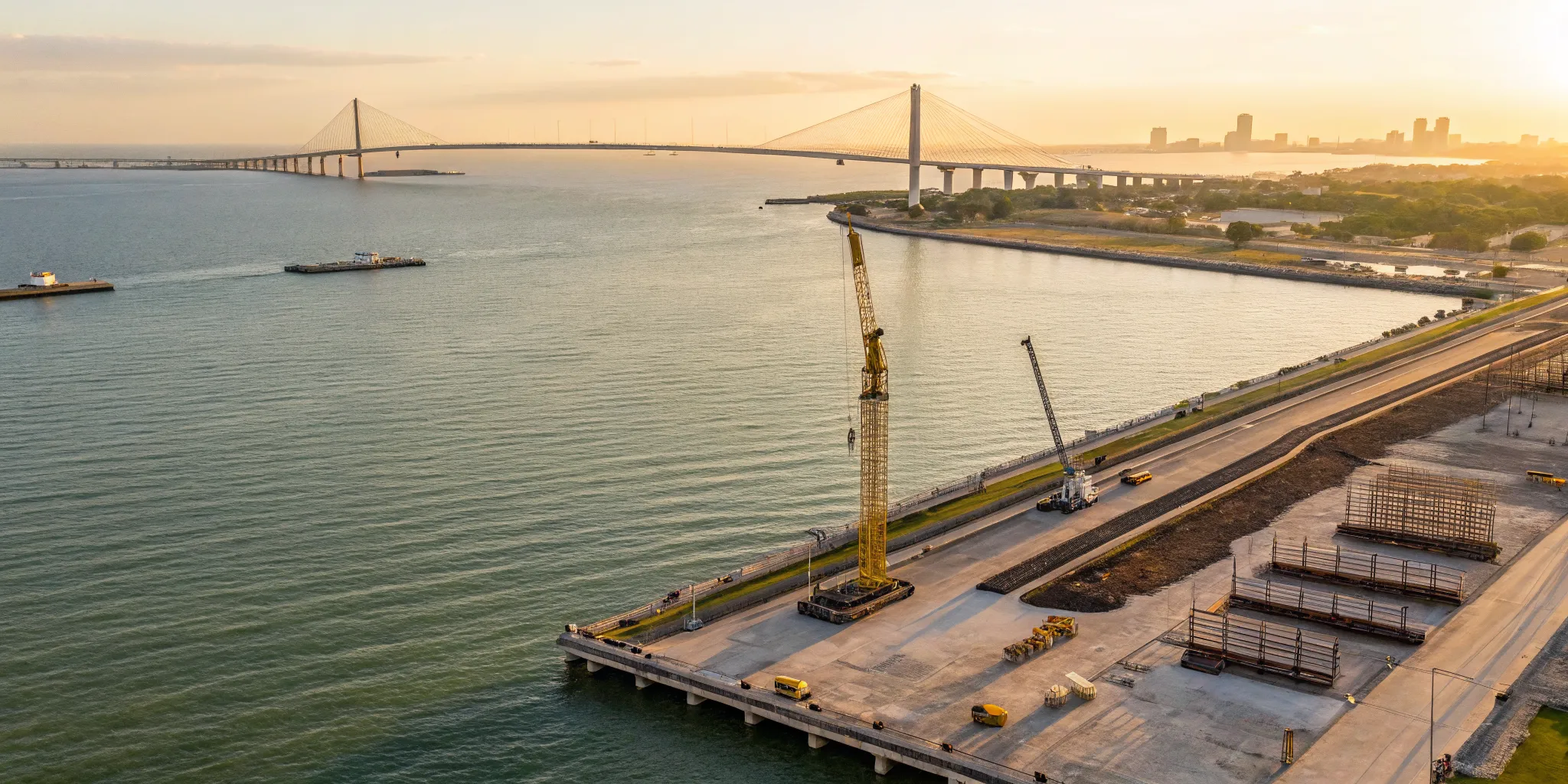Corpus Christi Harbor Bridge construction project with cranes over the waterfront at sunset.