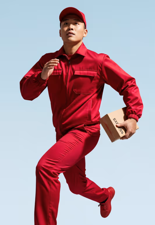 Delivery person in red uniform and cap running while holding a small express package.