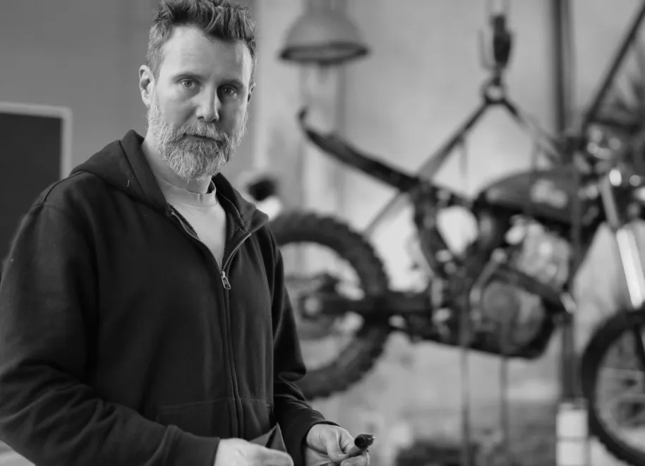 Smiling man driving a car with a woman holding a clipboard in the passenger seat.