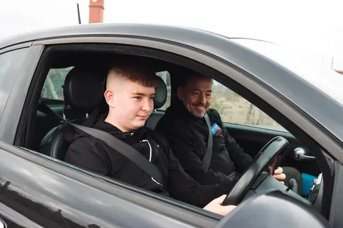 A male student driver receiving instruction from a Teesside School of Motoring instructor while behind the wheel of a car