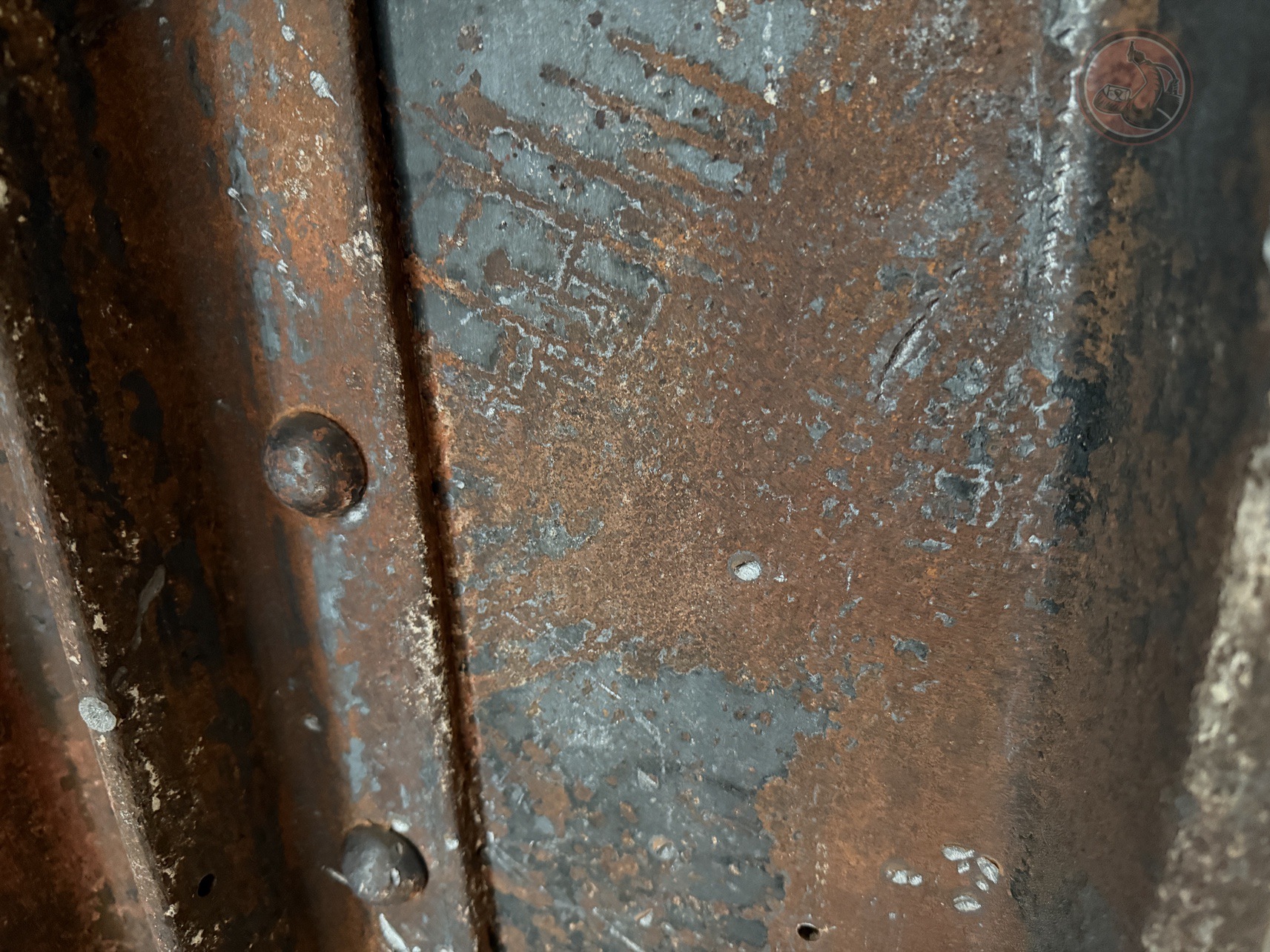 Close-up of rusted and corroded structural steel with visible rivets and flaking paint.