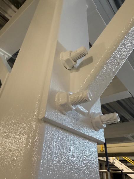 Close-up of a bolted steel connection with a completed white coating finish.