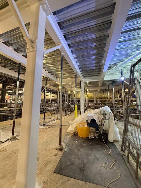 Completed white-coated column and beams beside the protected work area.