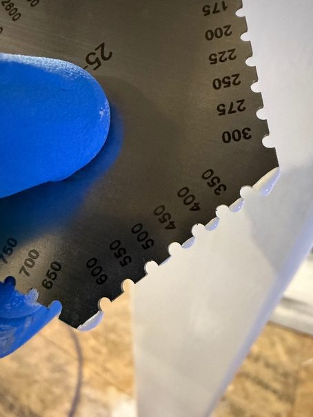 Close-up of a wet-film thickness measurement on white intumescent coating.