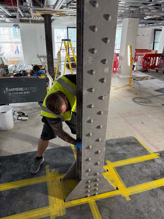 Exposed steel columns at different stages of coating at Devonshire House.
