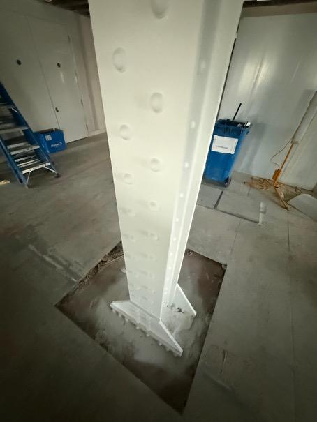 Close-up of the white-coated riveted steel column and base plate.