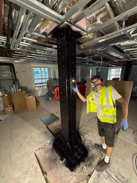 Operative applying the black finish to a steel column at Devonshire House.