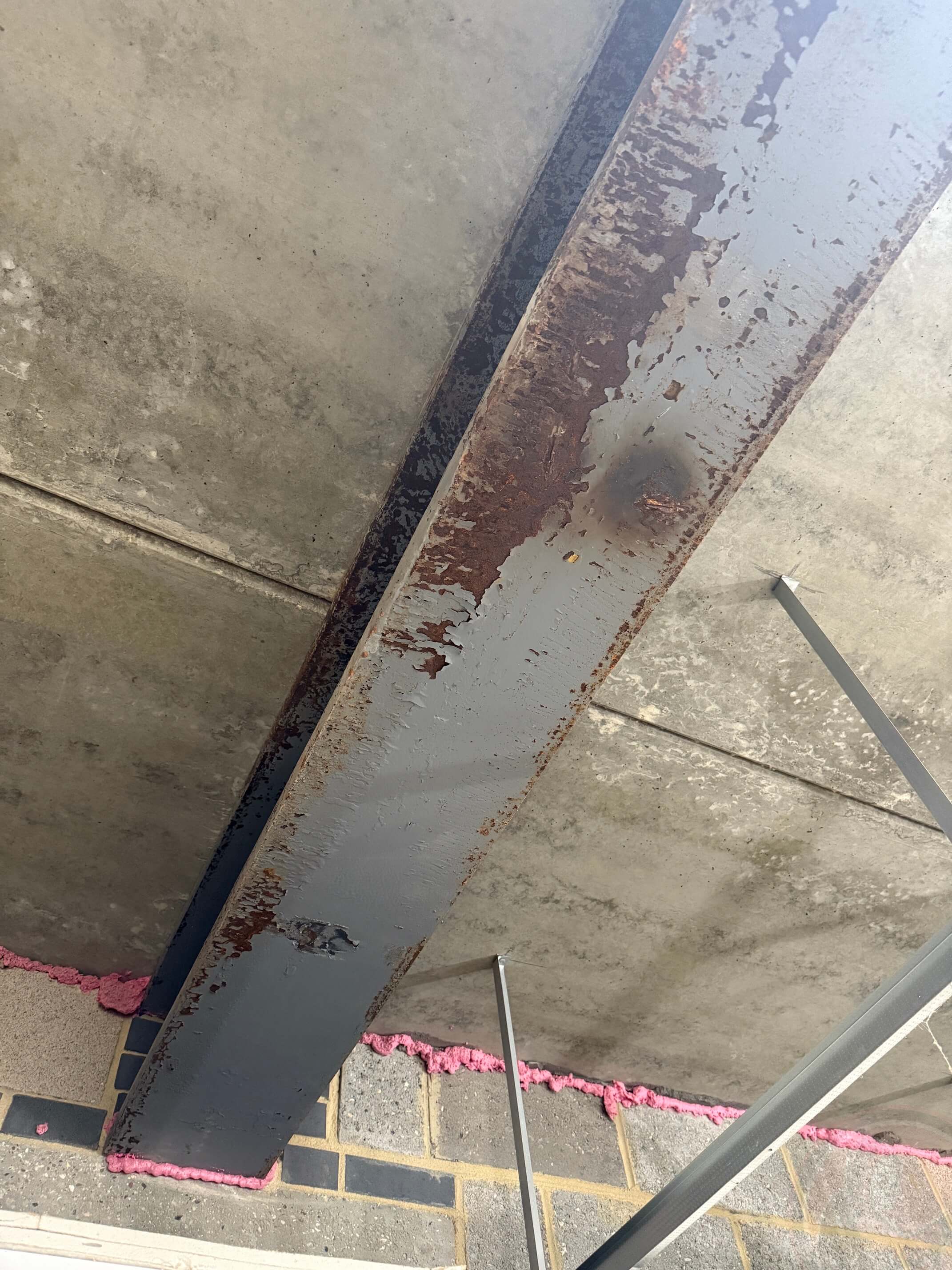 Flaking paint and rust on structural steel before abrasive blasting.