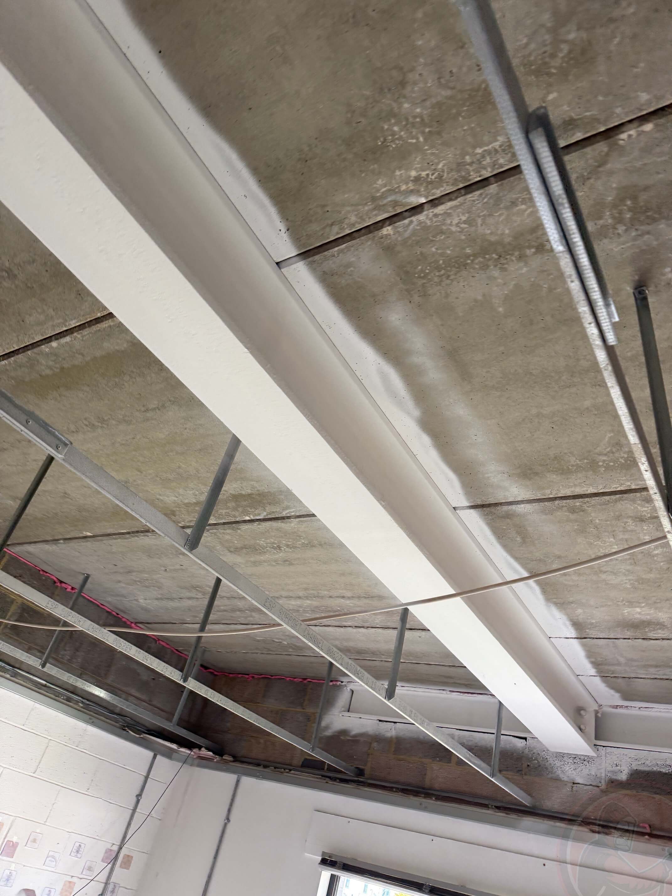 Overhead steel beams with completed white intumescent coating.