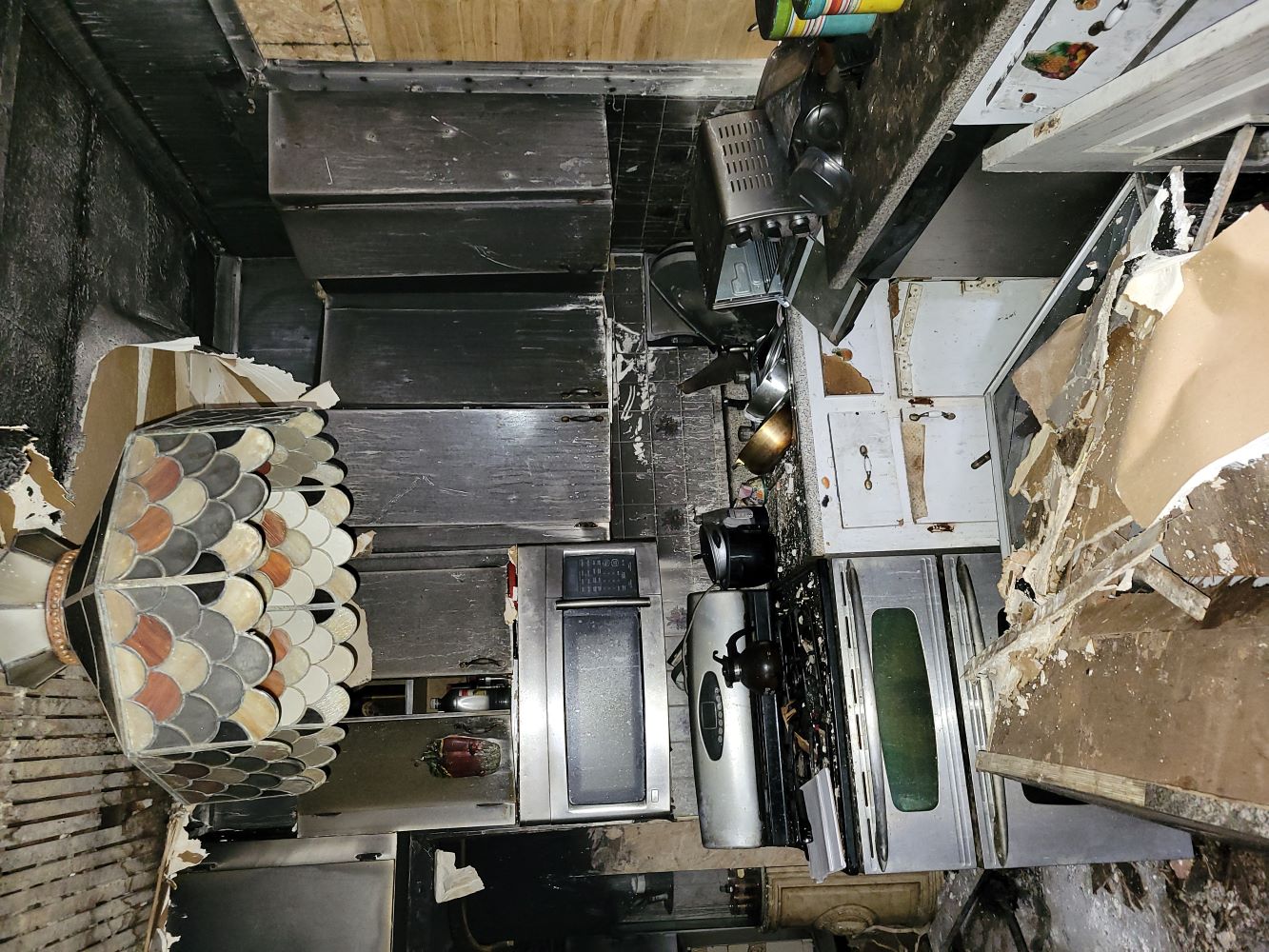 Construction workers repairing a two-story house with extensive fire damage on its front exterior.
