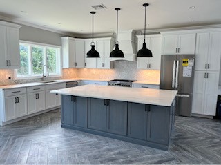 Modern kitchen with white cabinetry, a stainless steel stove with a light blue kettle, and a blue patterned tile backsplash.