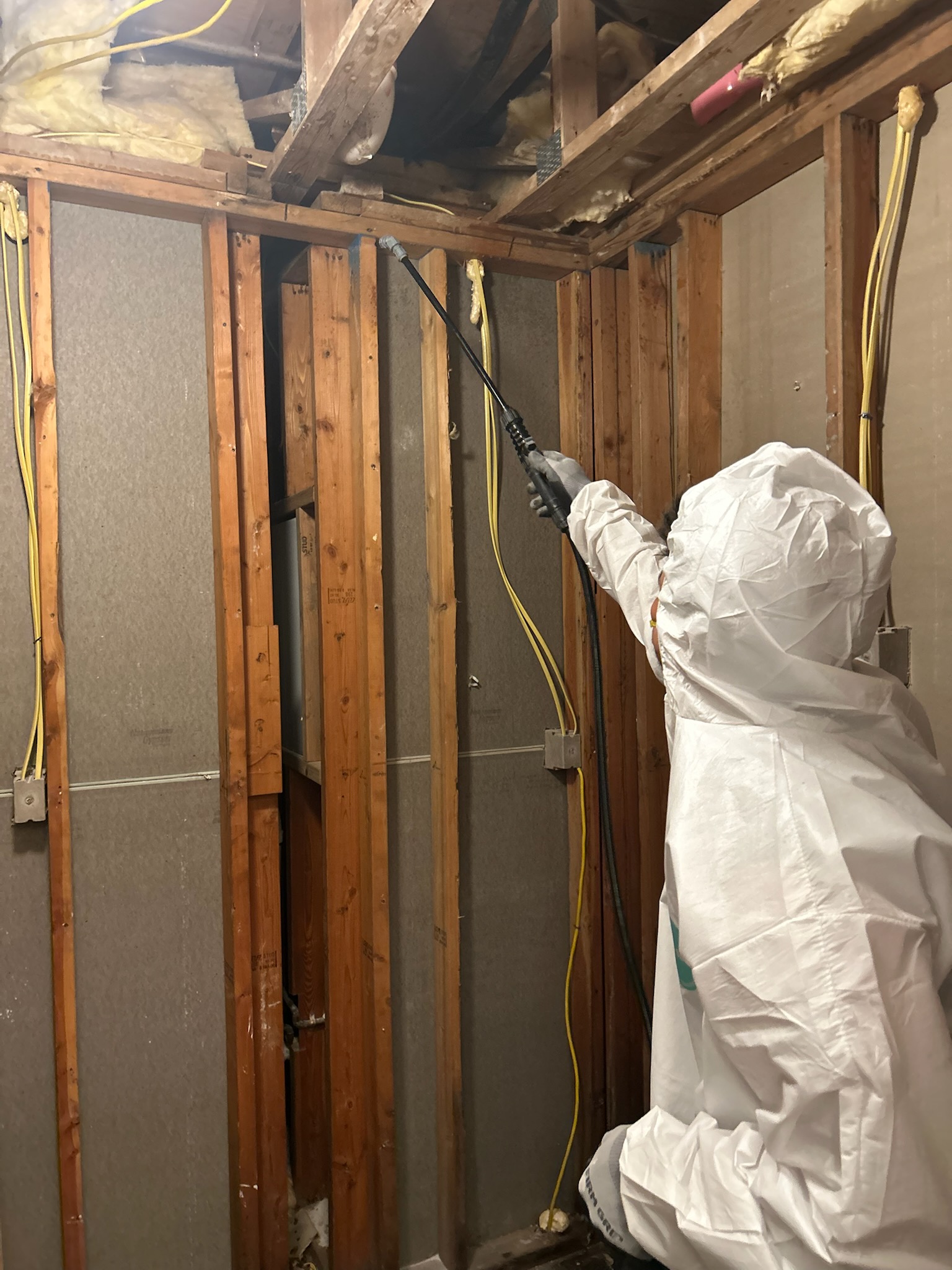 Side of a building with fire damage including charred siding and a burnt window air conditioner with metal bars.