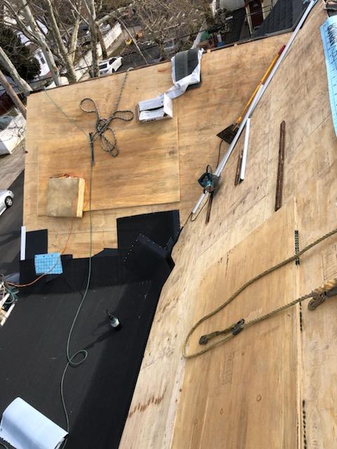 Cozy house exterior with three dormer windows, flower boxes, and leafy green shrubs in the foreground.