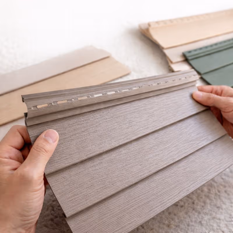 Two-story house with white siding, black garage door, stone stairs, and greenery climbing the exterior walls.