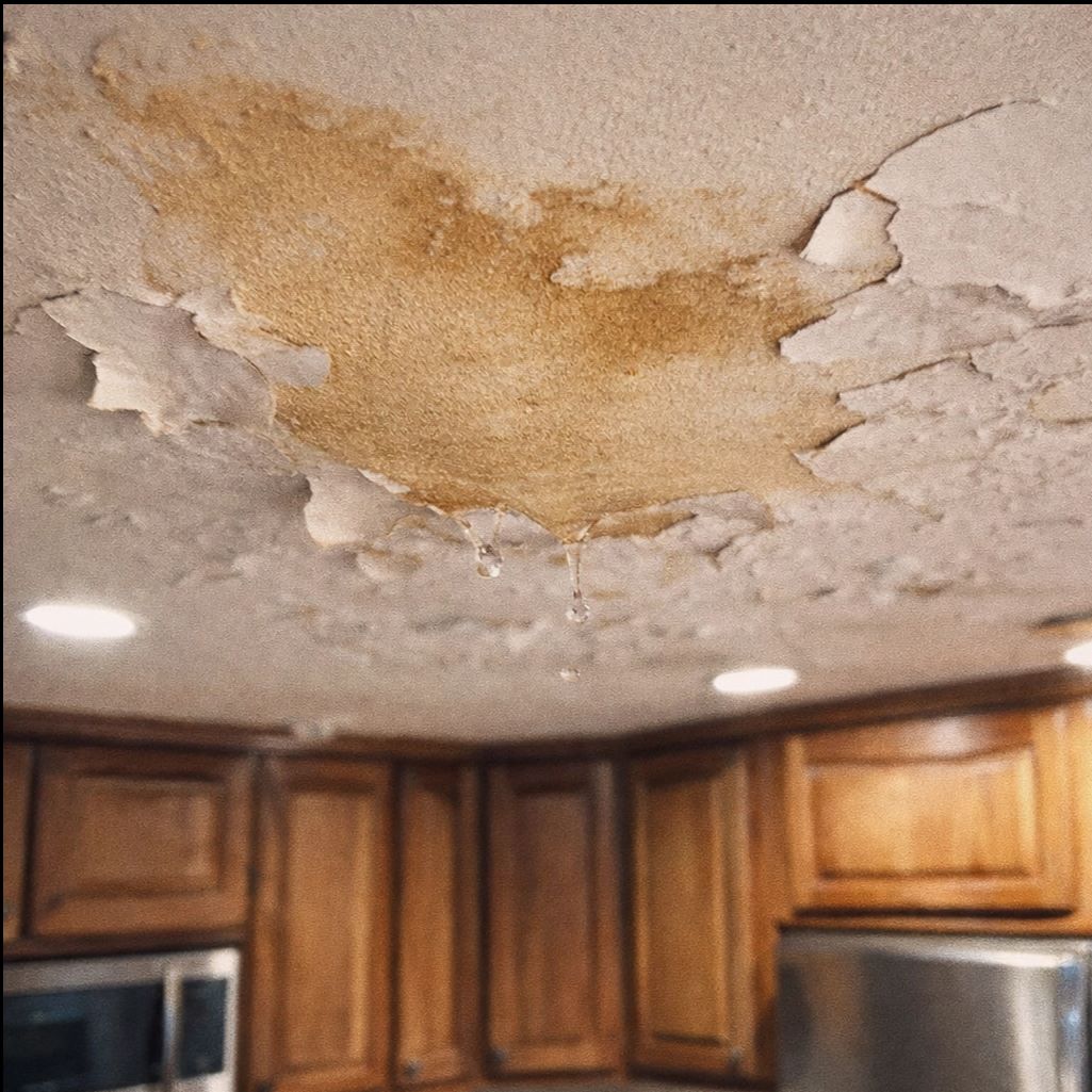 Two workers in white hazmat suits and respirators removing mold from a wall inside a room.
