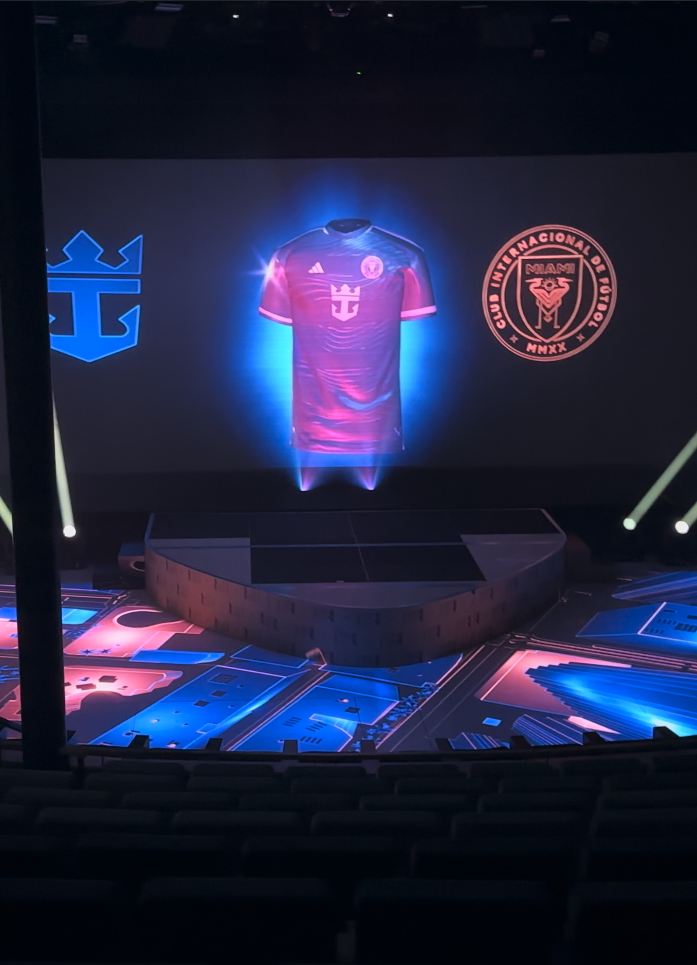 Stage with a holographic display of a pink soccer jersey flanked by the Royal Caribbean logo on the left and the Inter Miami CF crest on the right.