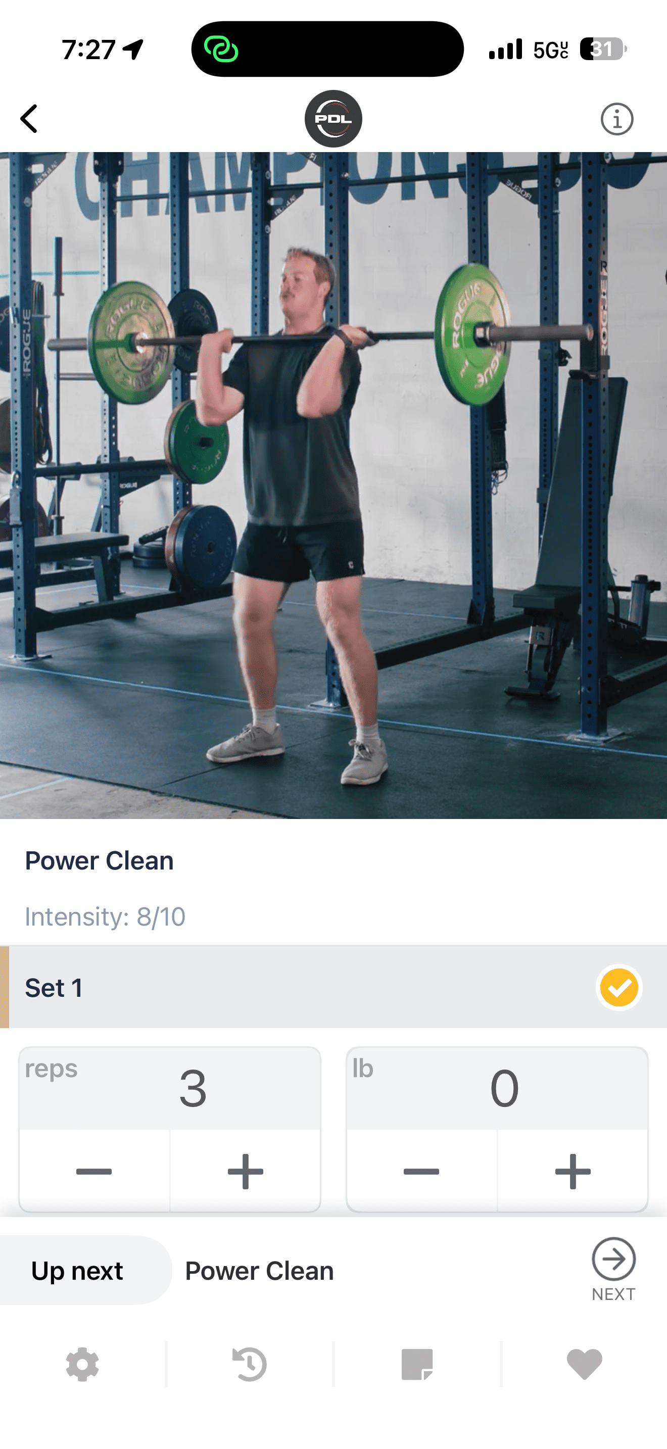 Man performing a power clean exercise with a barbell in a gym setting.