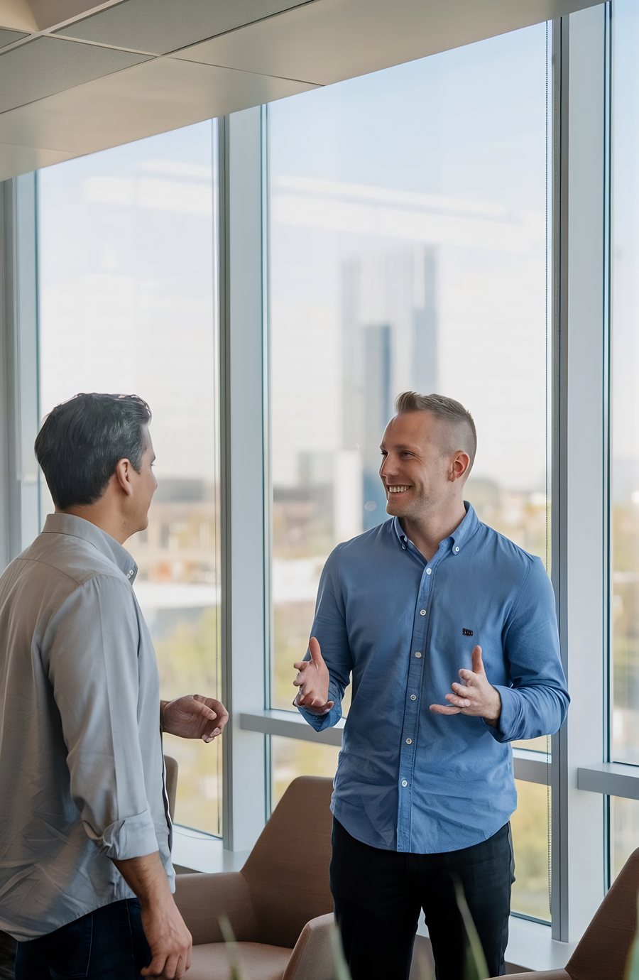 Two senior professionals in conversation beside an office window