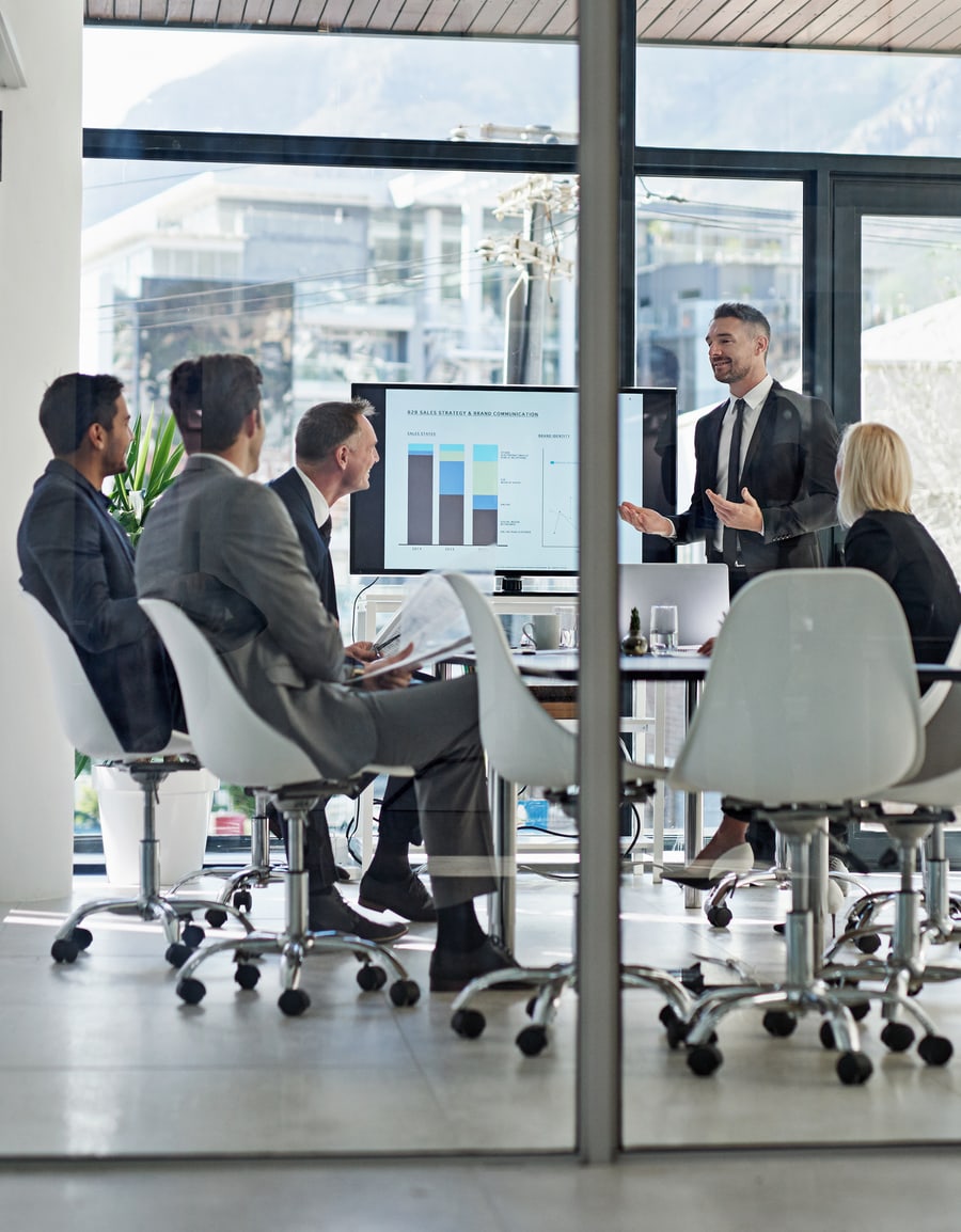 A strategy deck being presented to a boardroom, seen through a glass wall