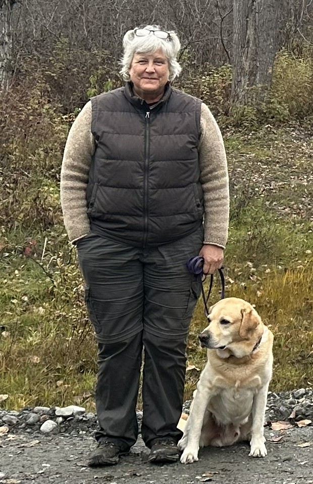 Kathleen standing with her dog Seamus in the woods.