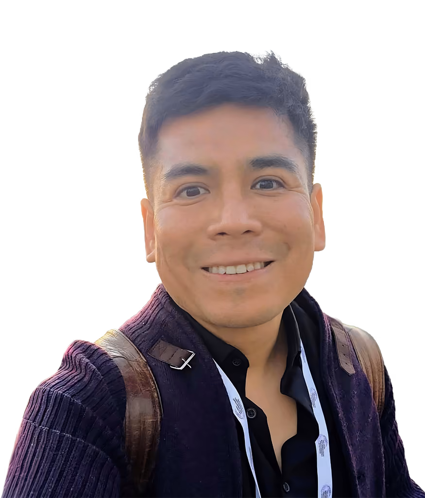 Hombre calvo con gafas redondas oscuras, camisa beige y collar de perlas sonriente.