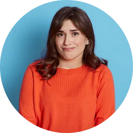 Woman with dark brown hair wearing an orange sweater standing against a light blue background with a slight smile.
