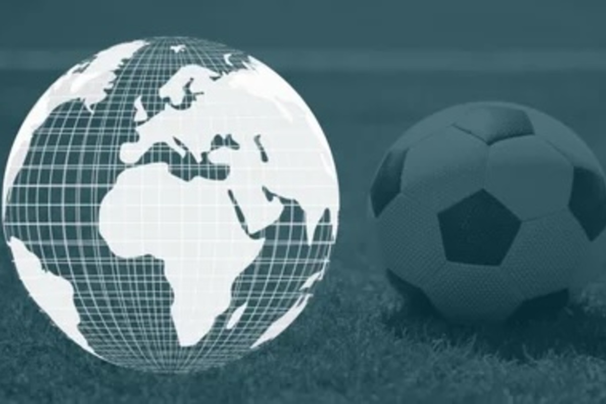 A digital globe showing Africa and Europe next to a soccer ball placed on grass.