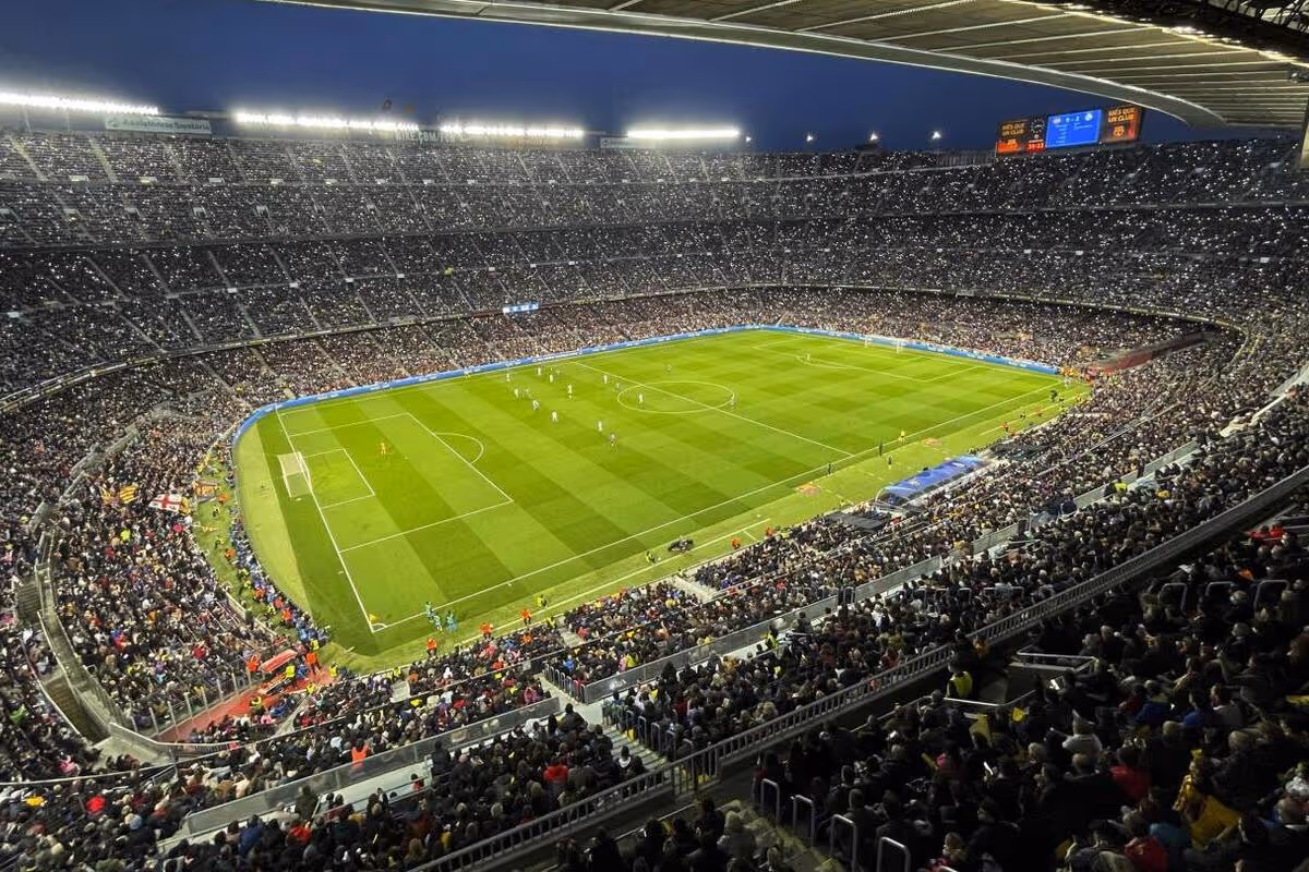 Children playing soccer outdoors, with a boy in red dribbling the ball while boys and girls in blue and red uniforms run beside him.