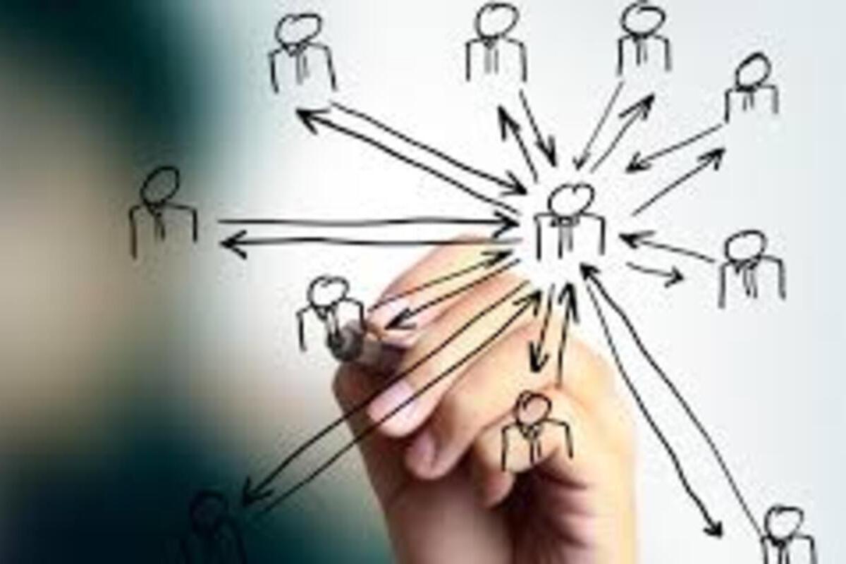 Group of young men in red shirts and black shorts walking with rolling suitcases toward a yellow aircraft boarding staircase attached to a parked airplane.