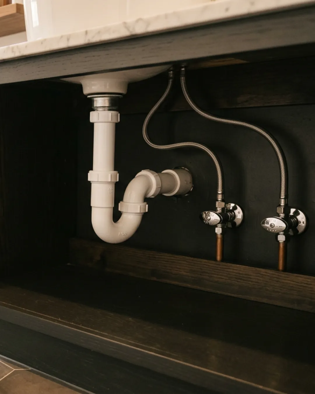 Clean PVC trap and pipe connections visible under an open bathroom vanity cabinet in a Balmain terrace