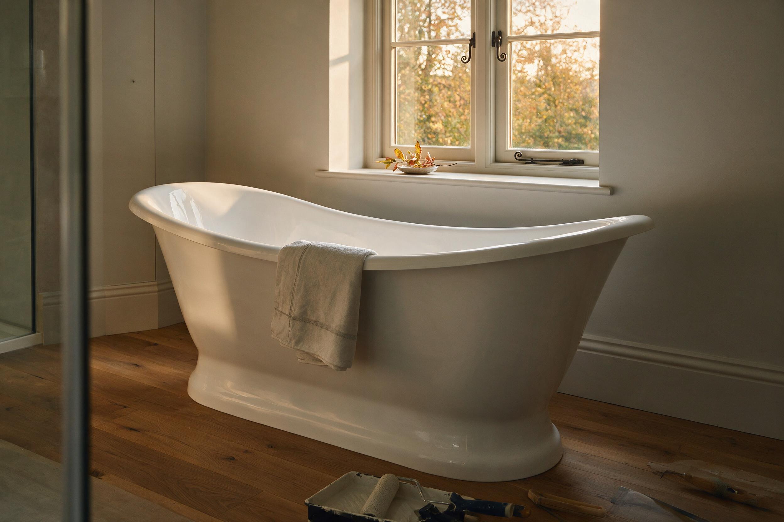 A freshly finished bathroom with a white freestanding bath, photographed in warm autumn light