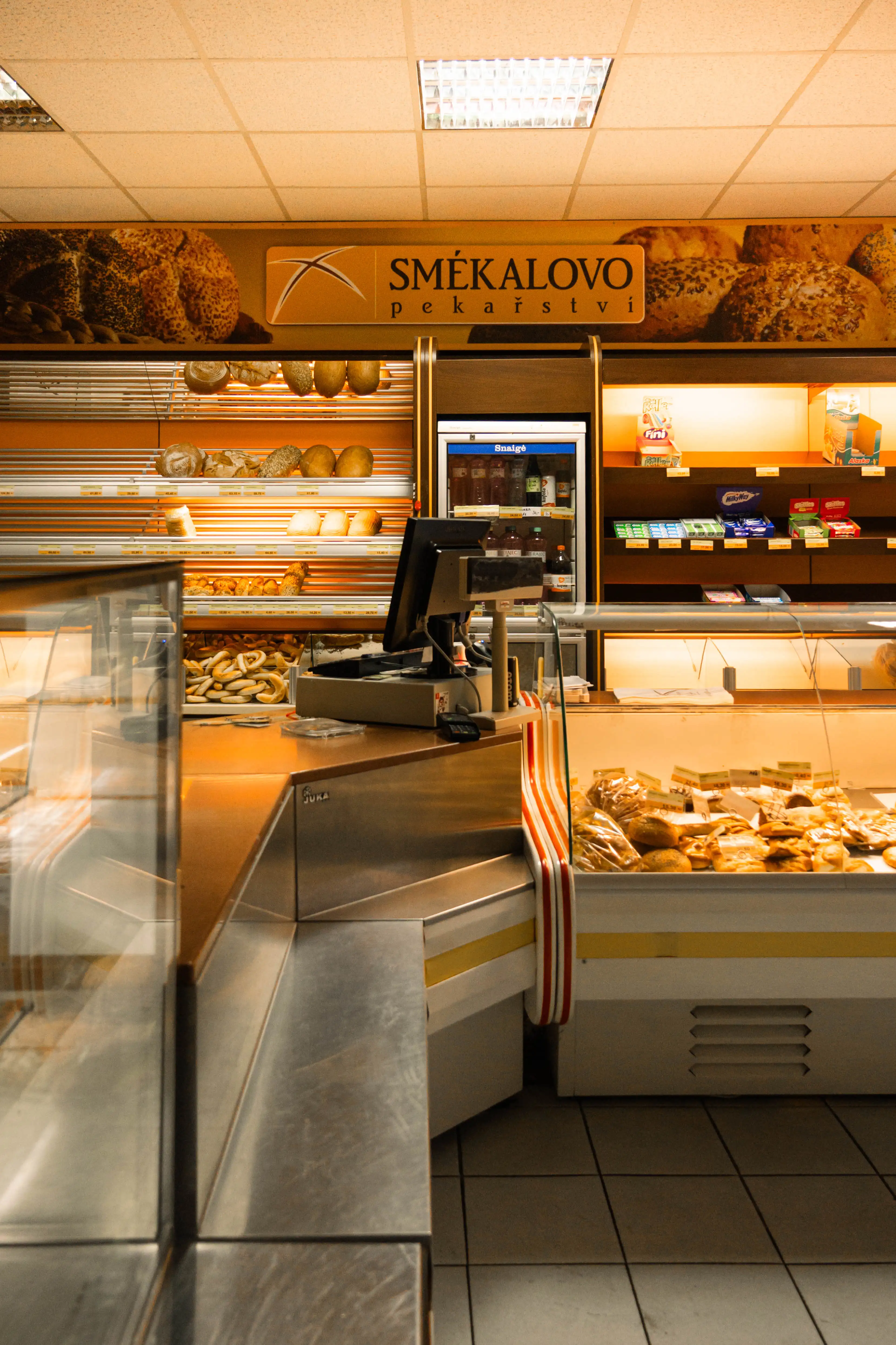 Pekárna s vitrínami plnými různých druhů pečiva a pokladnou uprostřed.