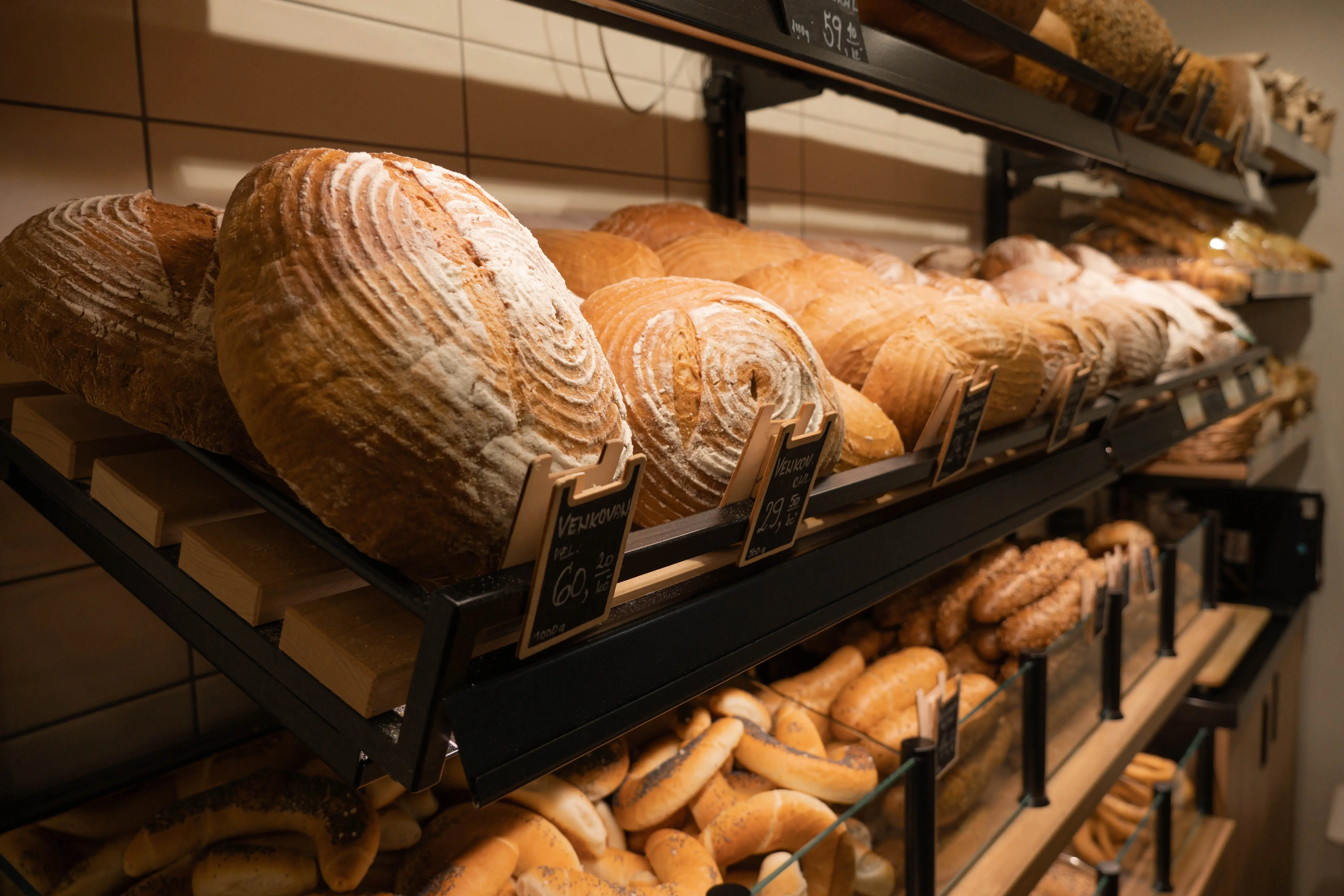 Regály v pekárně s různými druhy čerstvého chleba a pečiva.