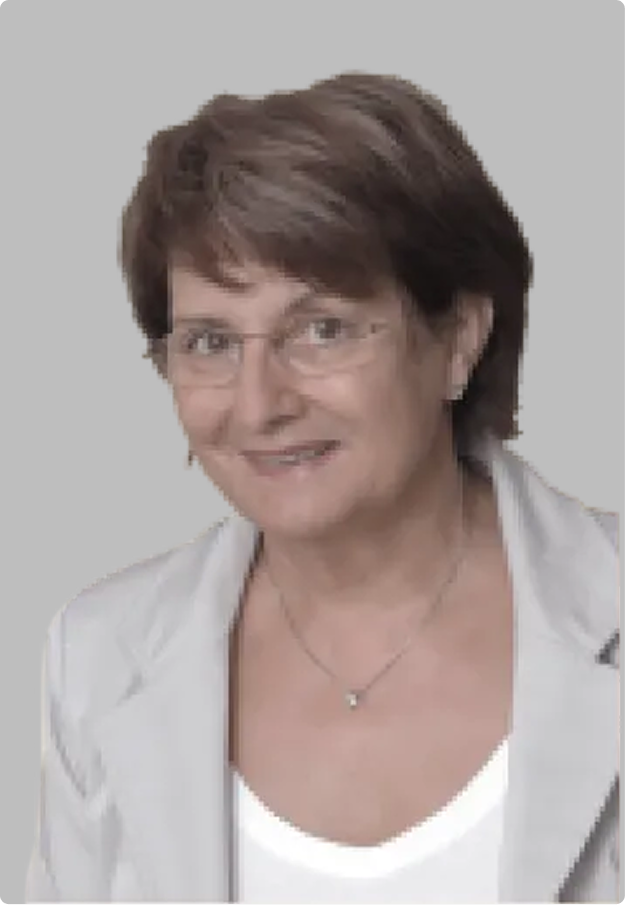 Žena středního věku s krátkými hnědými vlasy, brýlemi a bílým sakem na šedém pozadí.