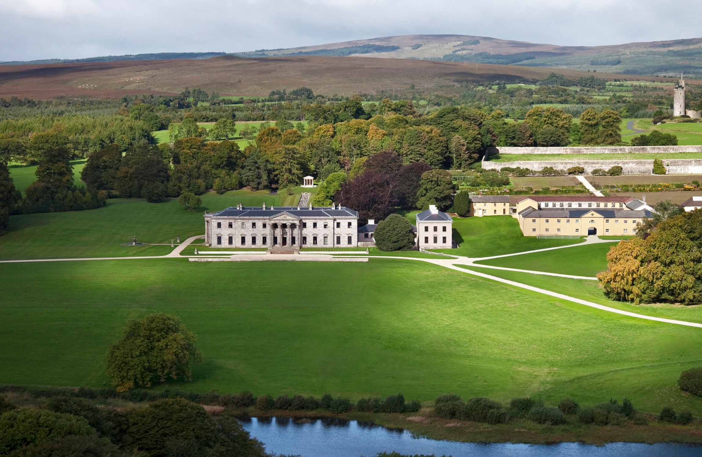 Aerial panoramic view of Ballyfin Demesne luxury country estate surrounded by gardens, lakes, and countryside in Ireland.