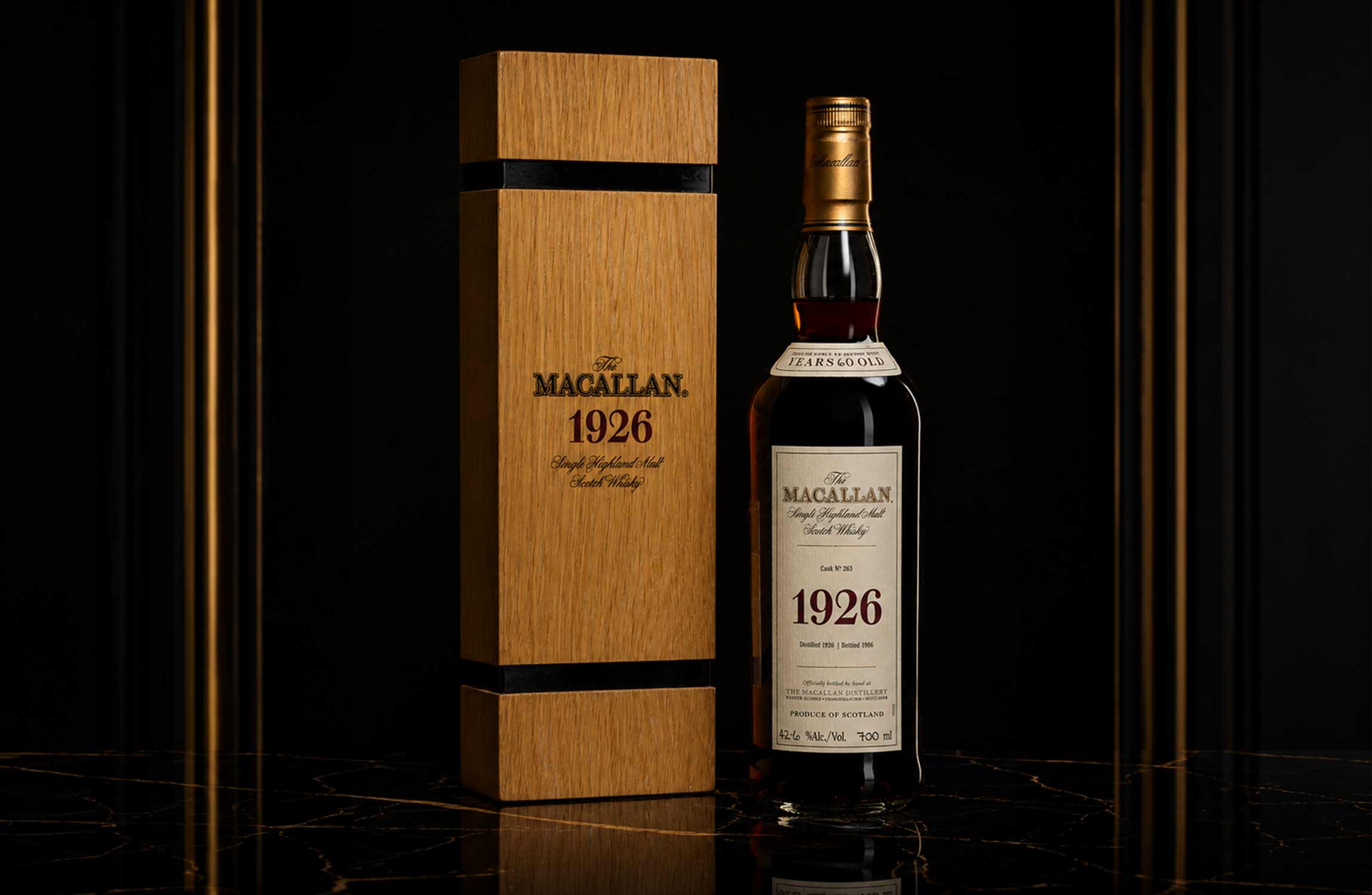 The Macallan 1926 whisky bottle and wooden case displayed on a black luxury background with dramatic lighting.