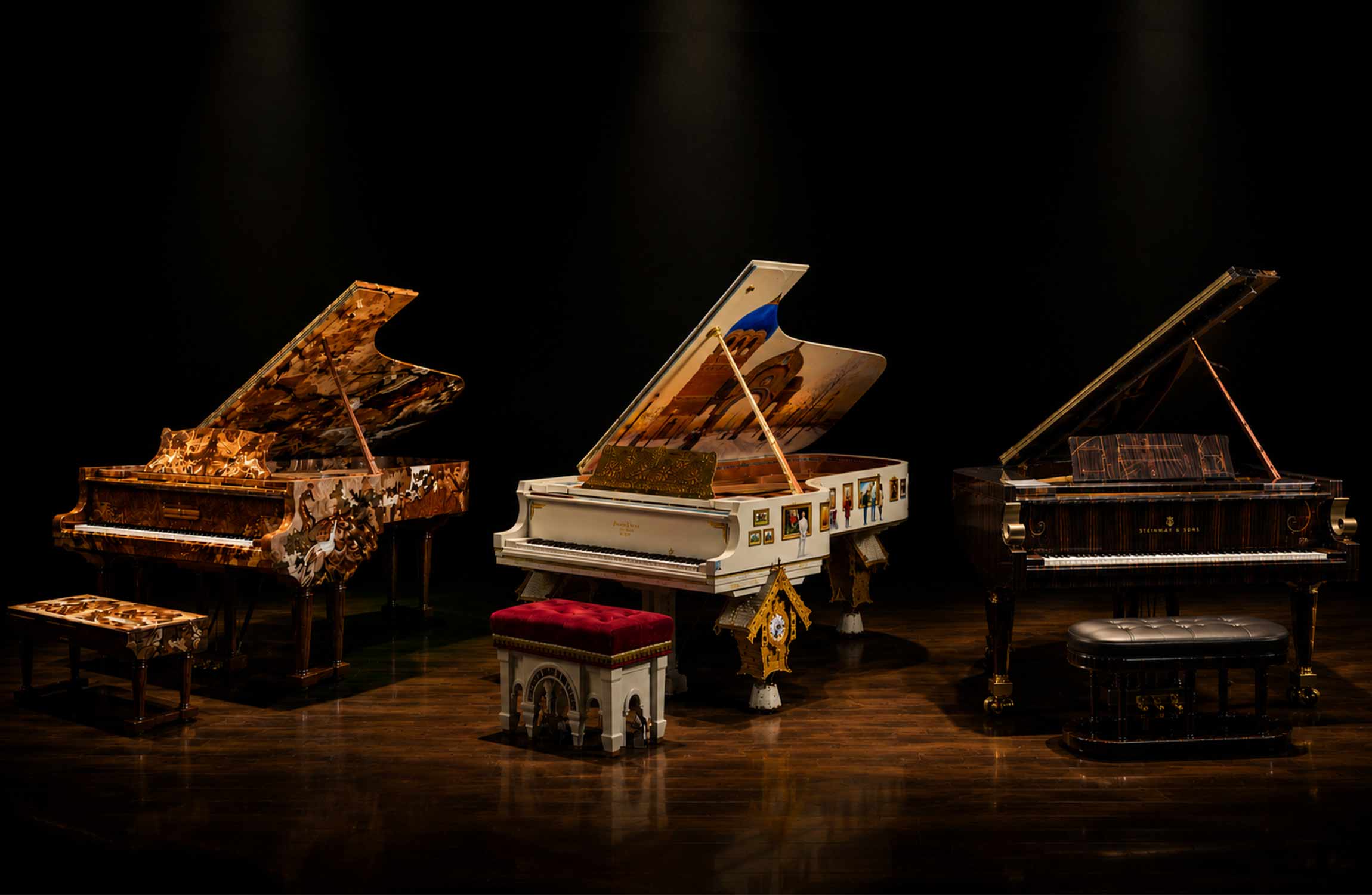 Three of the world's most expensive Steinway pianos displayed on a luxury concert stage under dramatic spotlights
