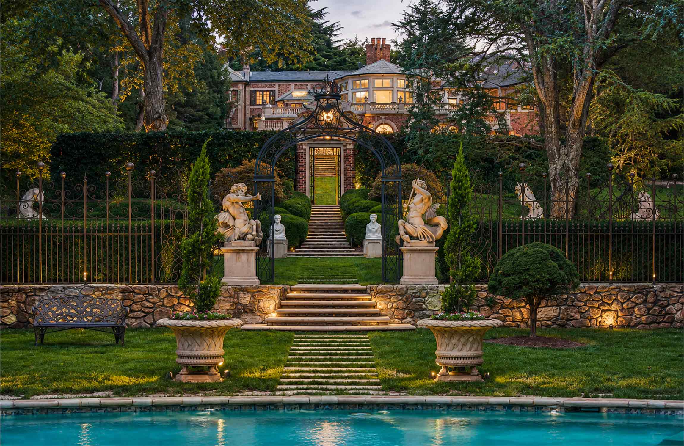 Formal gardens and swimming pool at Chestnut Hall, Atlanta's iconic English Tudor estate, featuring elegant wrought-iron gates, classical statues and beautifully landscaped grounds.