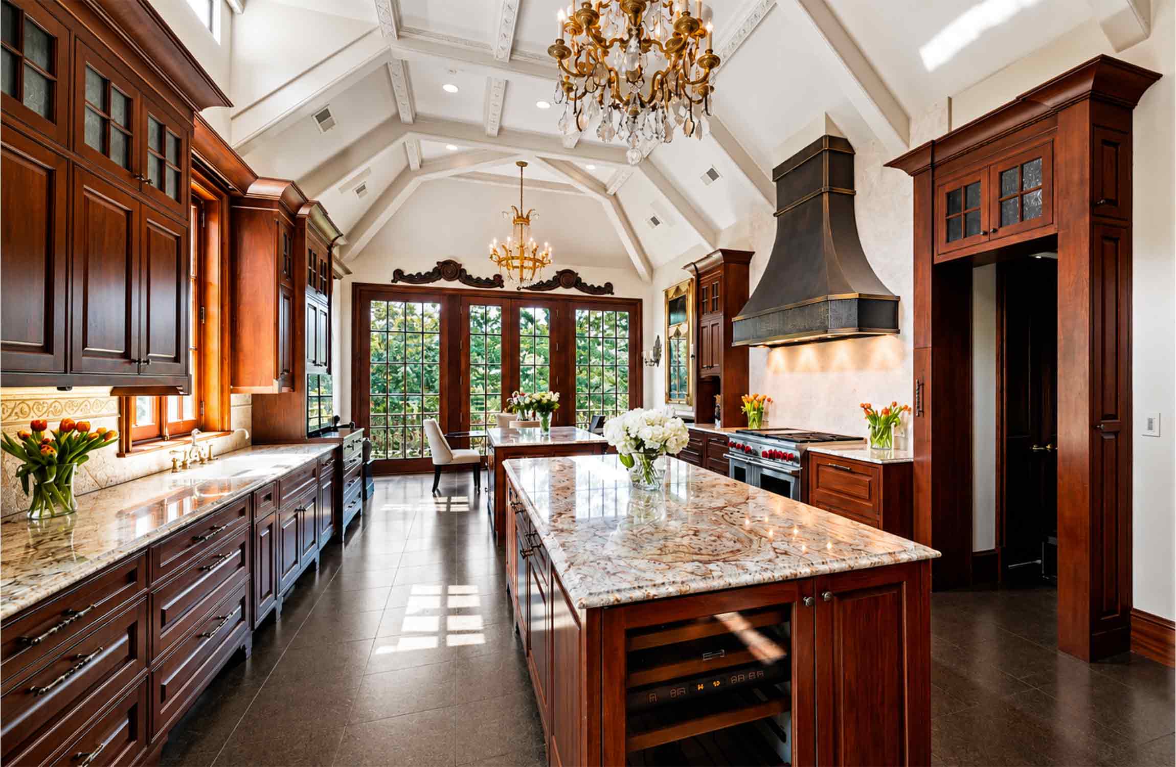 Gourmet chef's kitchen at Chestnut Hall, featuring handcrafted wood cabinetry, a large marble island, luxury appliances and soaring vaulted ceilings.
