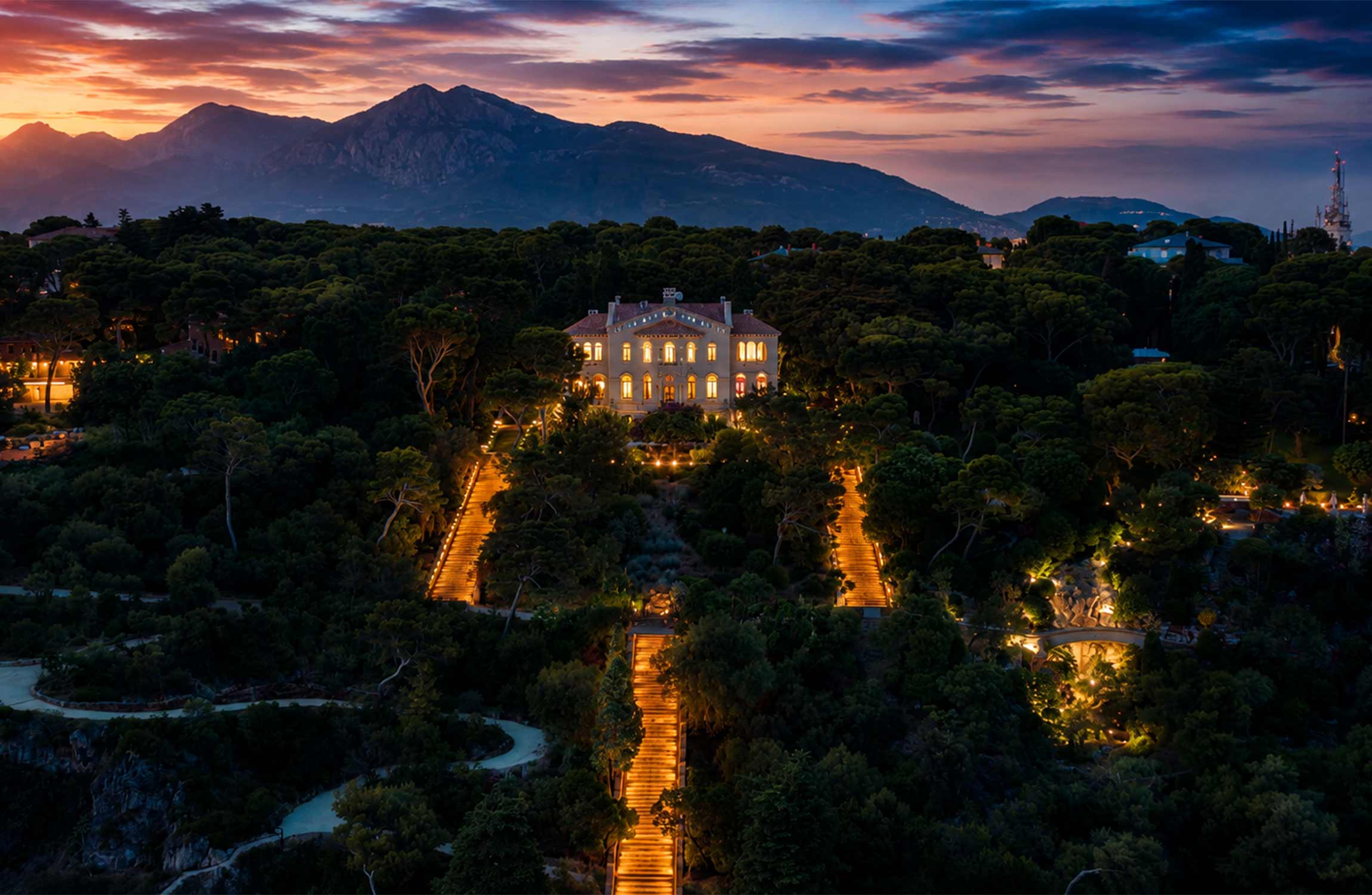 Villa Cypris illuminated at sunset in Roquebrune-Cap-Martin, surrounded by Mediterranean gardens and mountains near Monaco on the French Riviera.