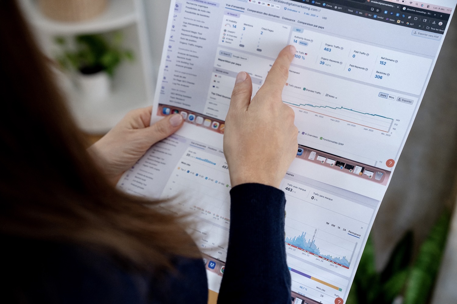 Person holding paper with digital marketing data charts and SEO metrics displayed.