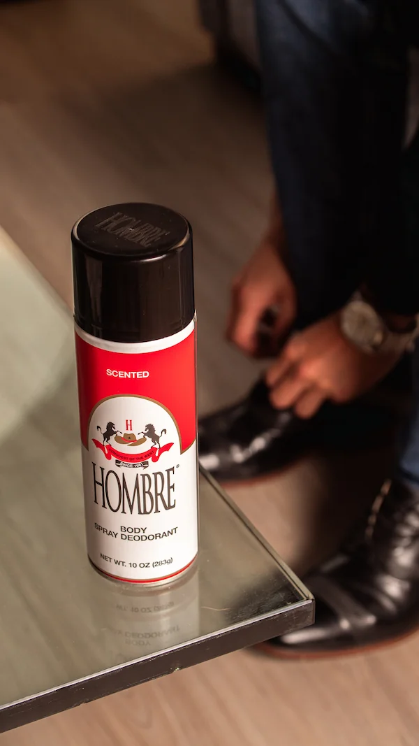 Man holding HOMBRE body spray deodorant can, premium grooming for men