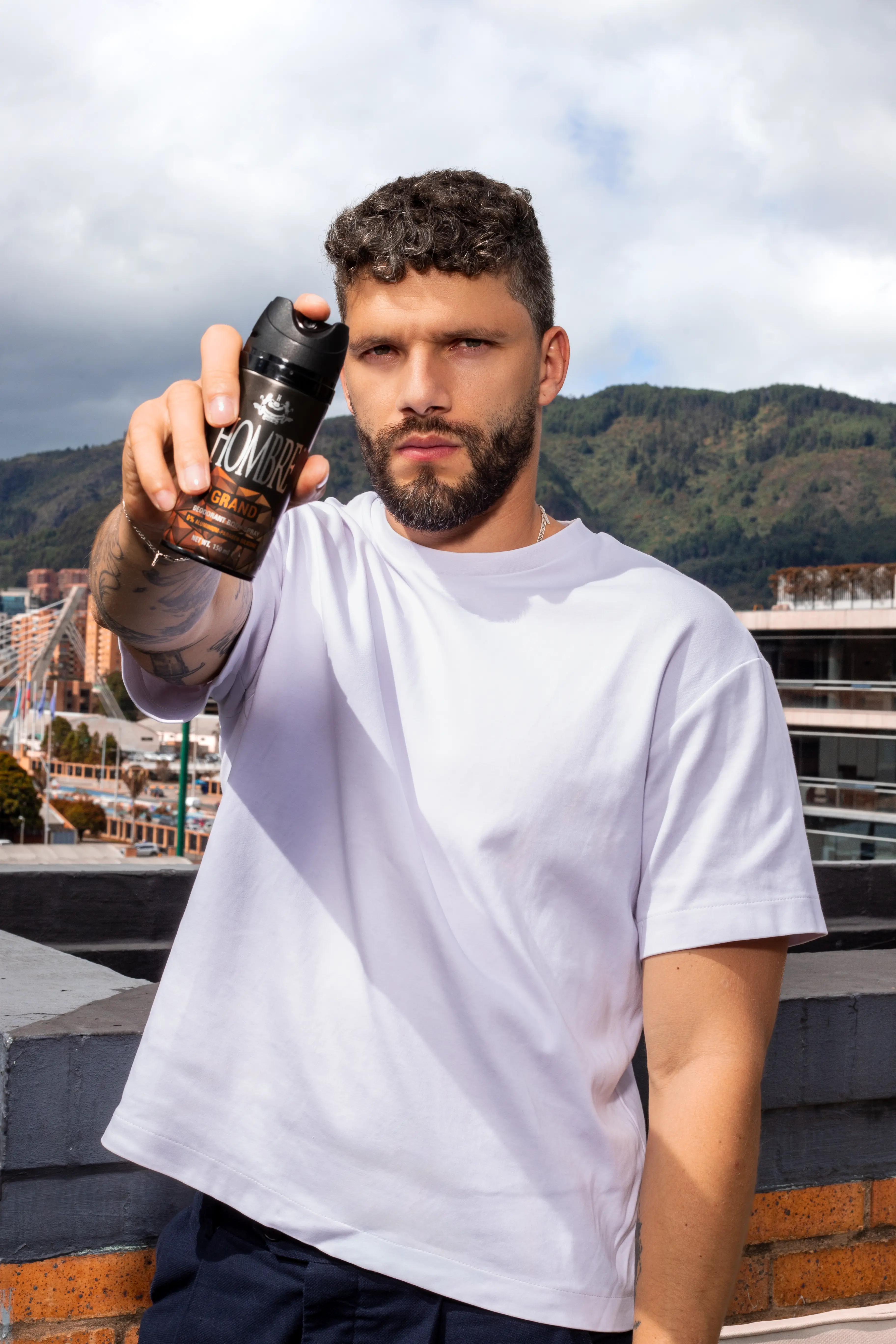 Man applying HOMBRE® Grand deodorant body spray outdoors — all-day odor protection for men