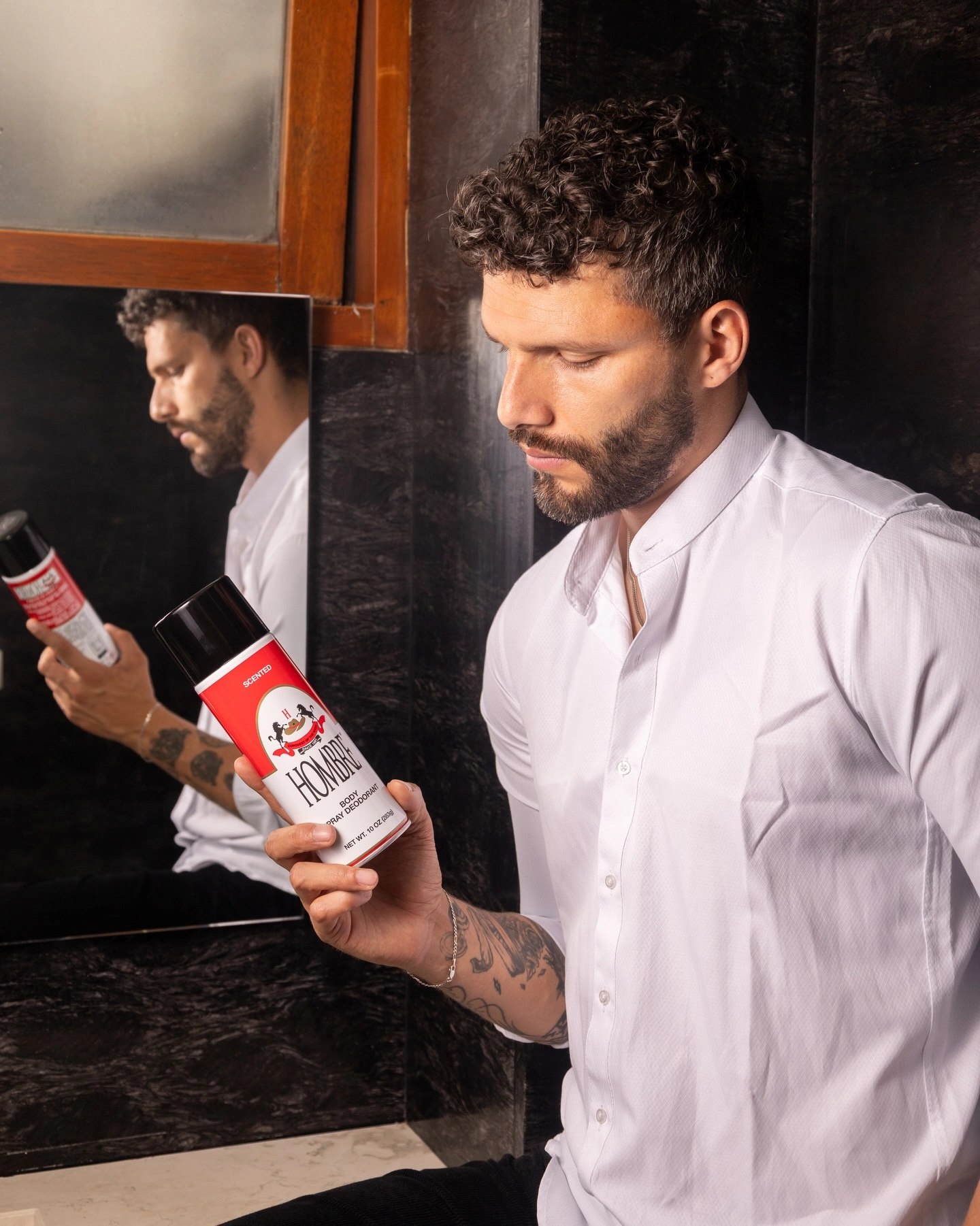 Man holding HOMBRE® Red classic deodorant body spray — timeless masculine fragrance for men