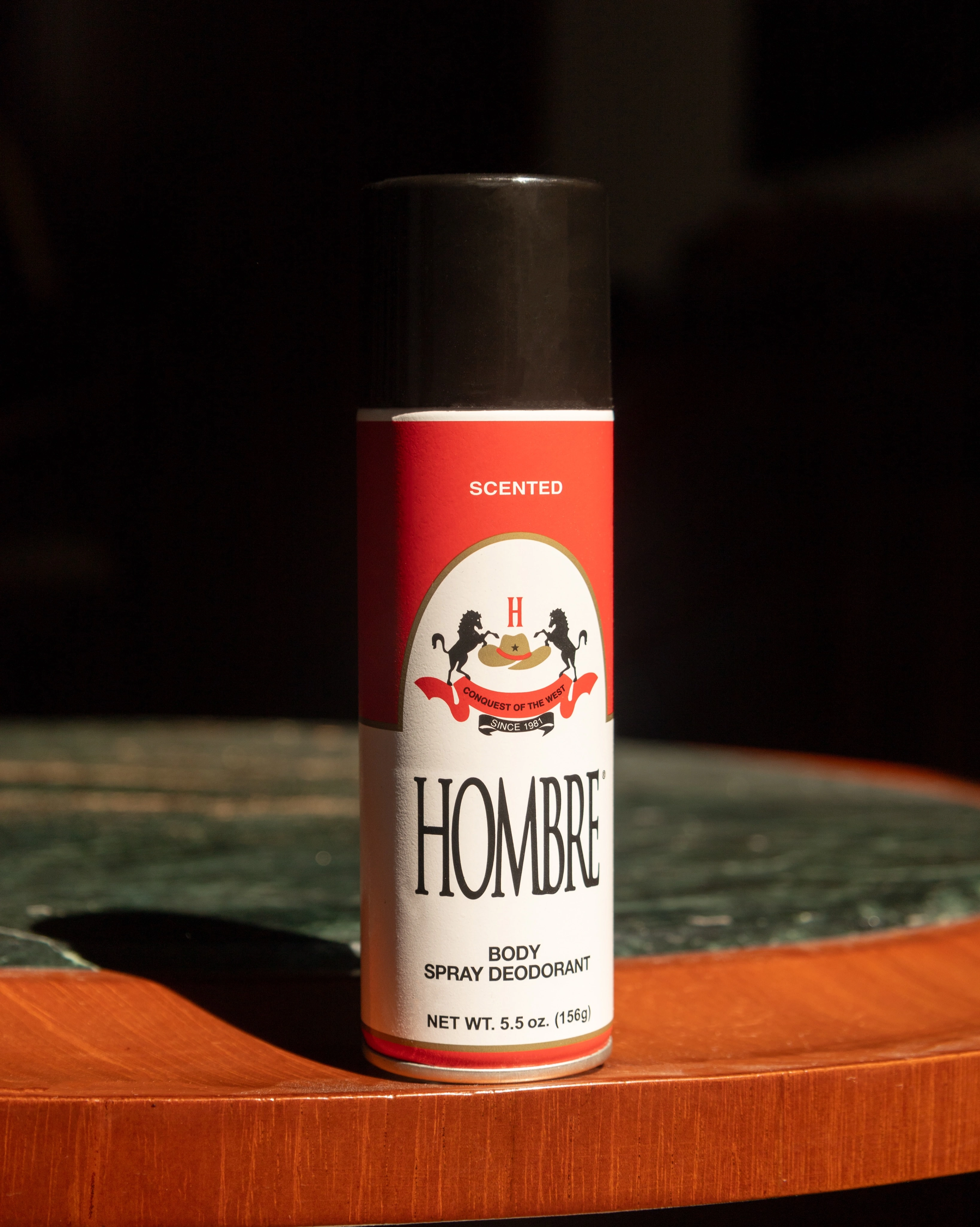 HOMBRE® Red deodorant body spray for men on warm background — warm spice scent with mandarin and musk