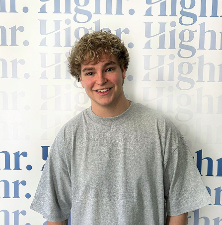Jonas Heitmann, Connection Specialist bei Highr, vor einer Highr Branding-Wand.