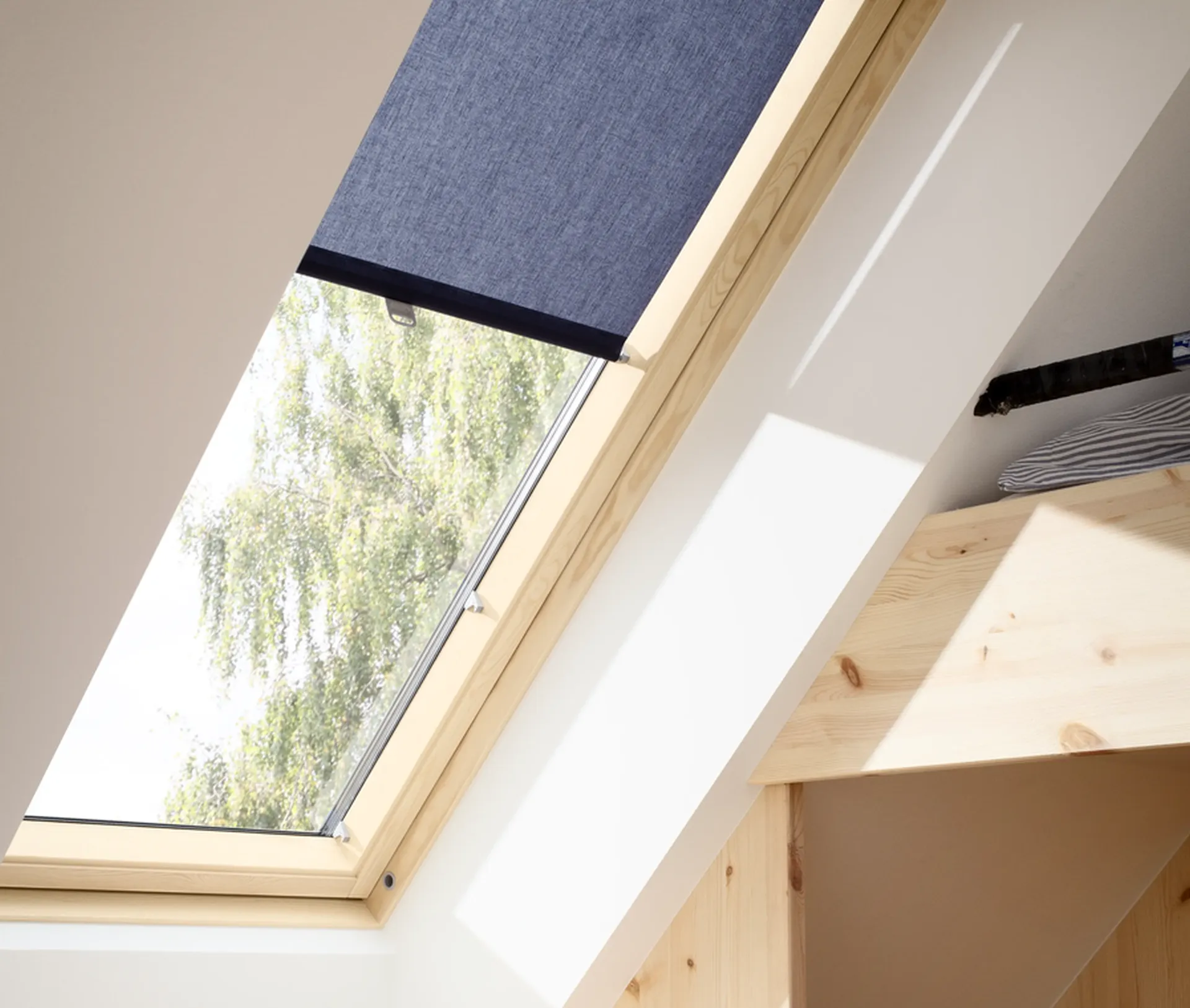 Zatemňovací roleta stažená na střešním okně VELUX. Součást podkrovní rekonstrukce.